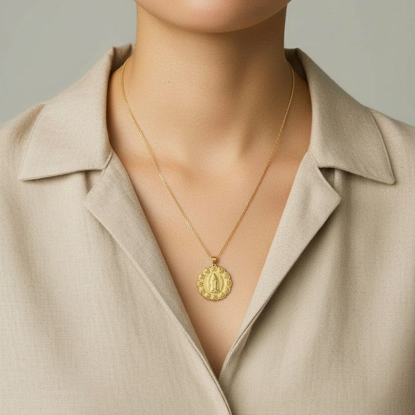 Close-up of a person wearing a gold necklace with a pendant against a neutral background