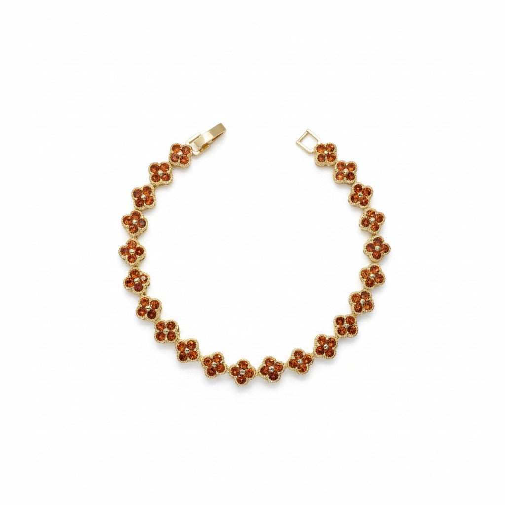 A gold-plated tennis bracelet featuring a series of small five-petal flower motifs filled with amber-brown inlay, displayed on a clean white background.