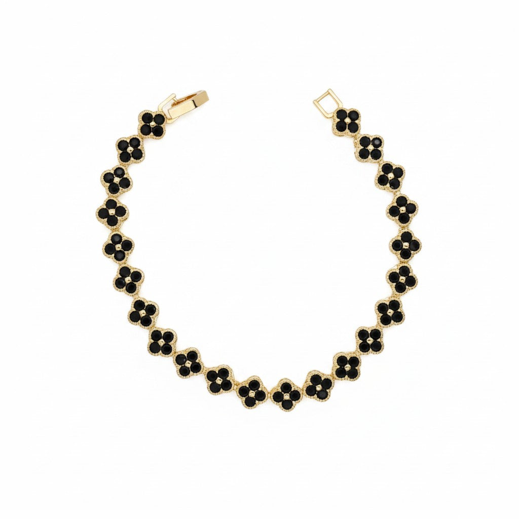 A gold-plated bracelet featuring a repeating pattern of black flower-shaped charms with small white center dots, displayed on a clean white background.