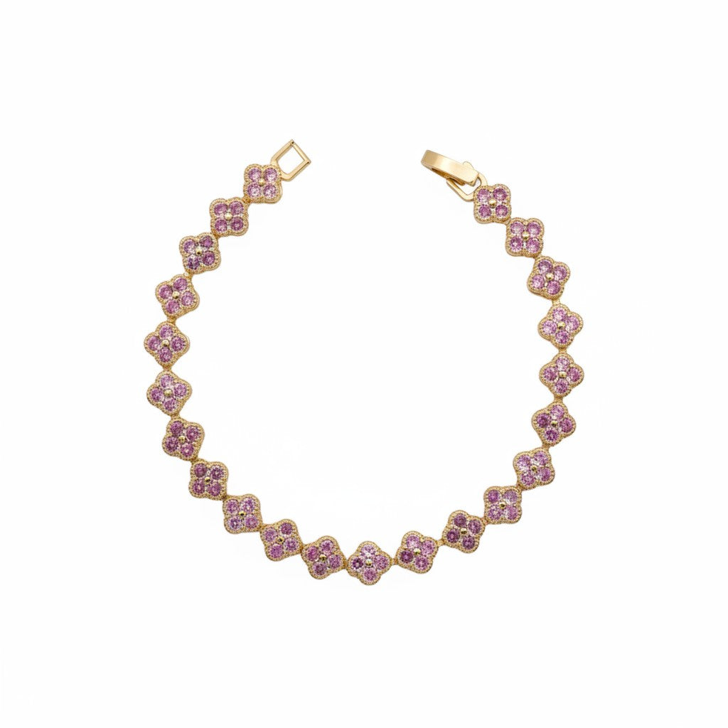 A gold-plated tennis bracelet featuring a repeating pattern of four-petal floral clusters set with small pink gemstones, displayed on a clean white background.